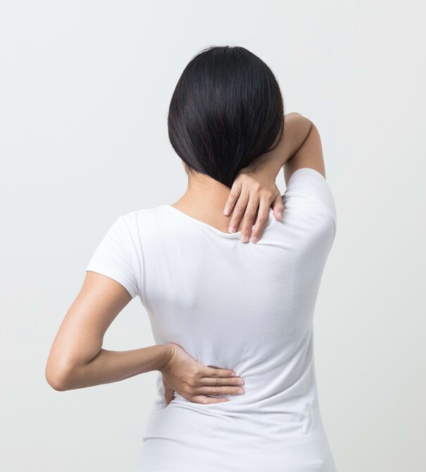 Frau mit Schmerzen im Nacken und dem unteren Ruecken